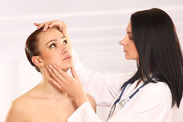 A doctor is examining a woman 's face with a stethoscope.