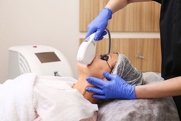 A woman is getting a laser treatment on her face.