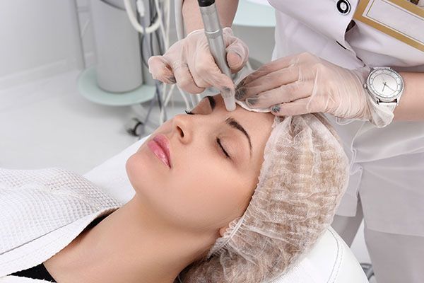 A woman is getting a tattoo on her eyebrows.