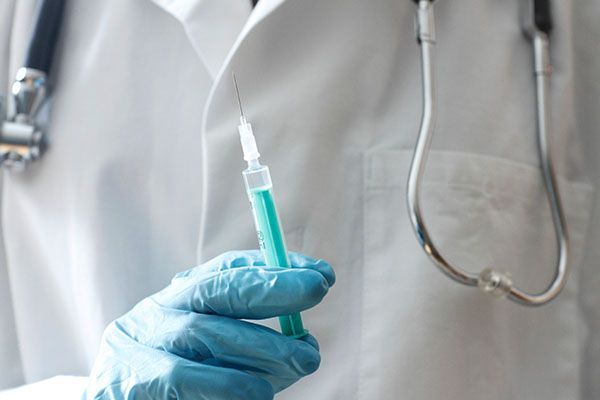 A doctor is holding a syringe in his hand.