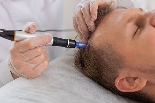 A man is getting a hair treatment from a doctor.
