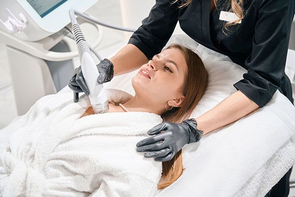 A woman is laying on a bed getting a facial treatment.