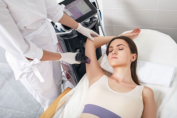 A woman is getting a laser hair removal treatment on her armpit.