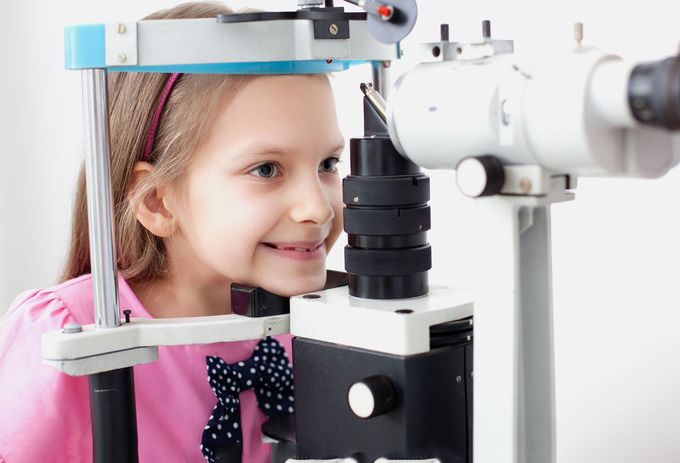 A little girl is getting her eyes examined by an ophthalmologist.