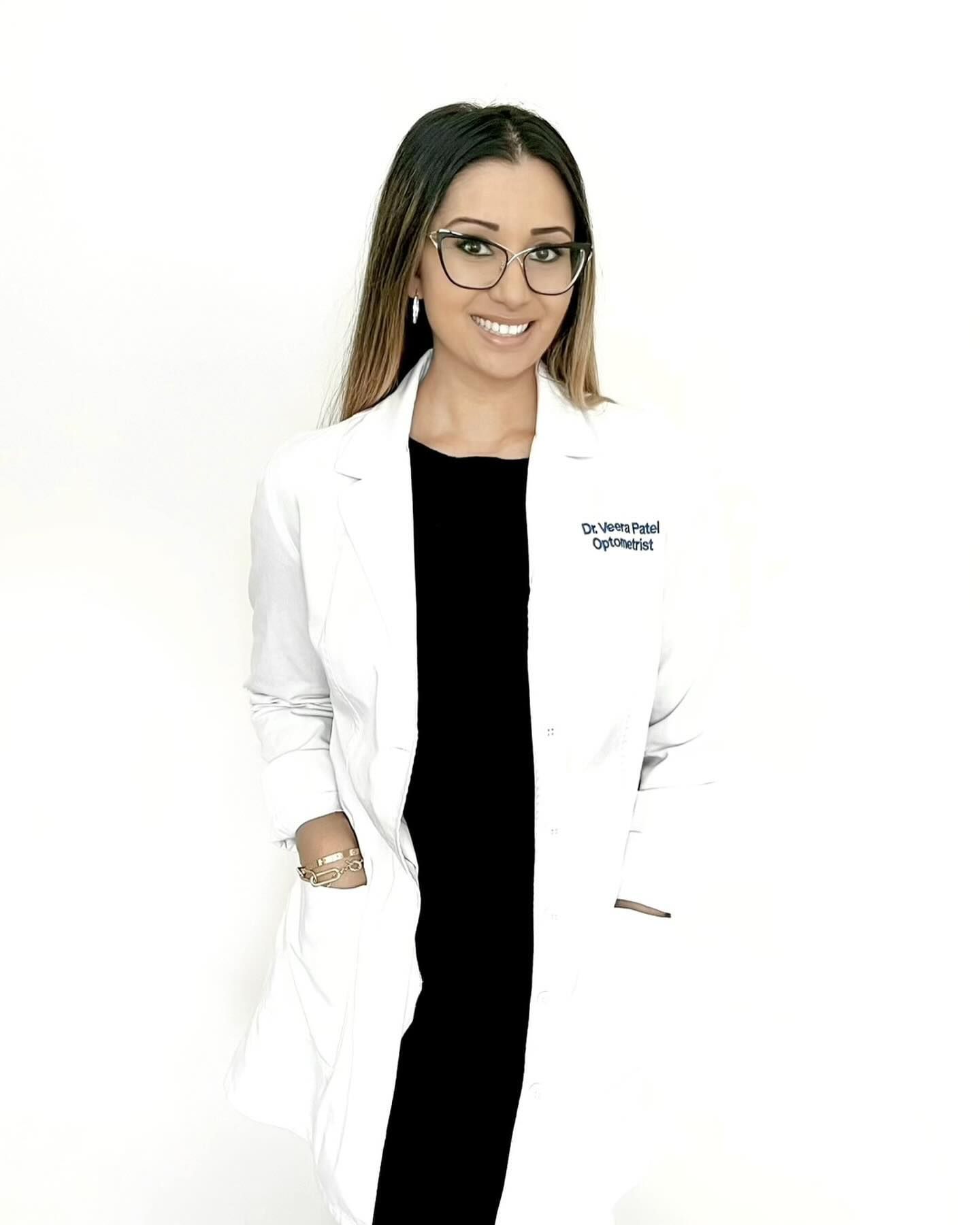 A woman wearing a white lab coat and glasses is standing in front of a white background.