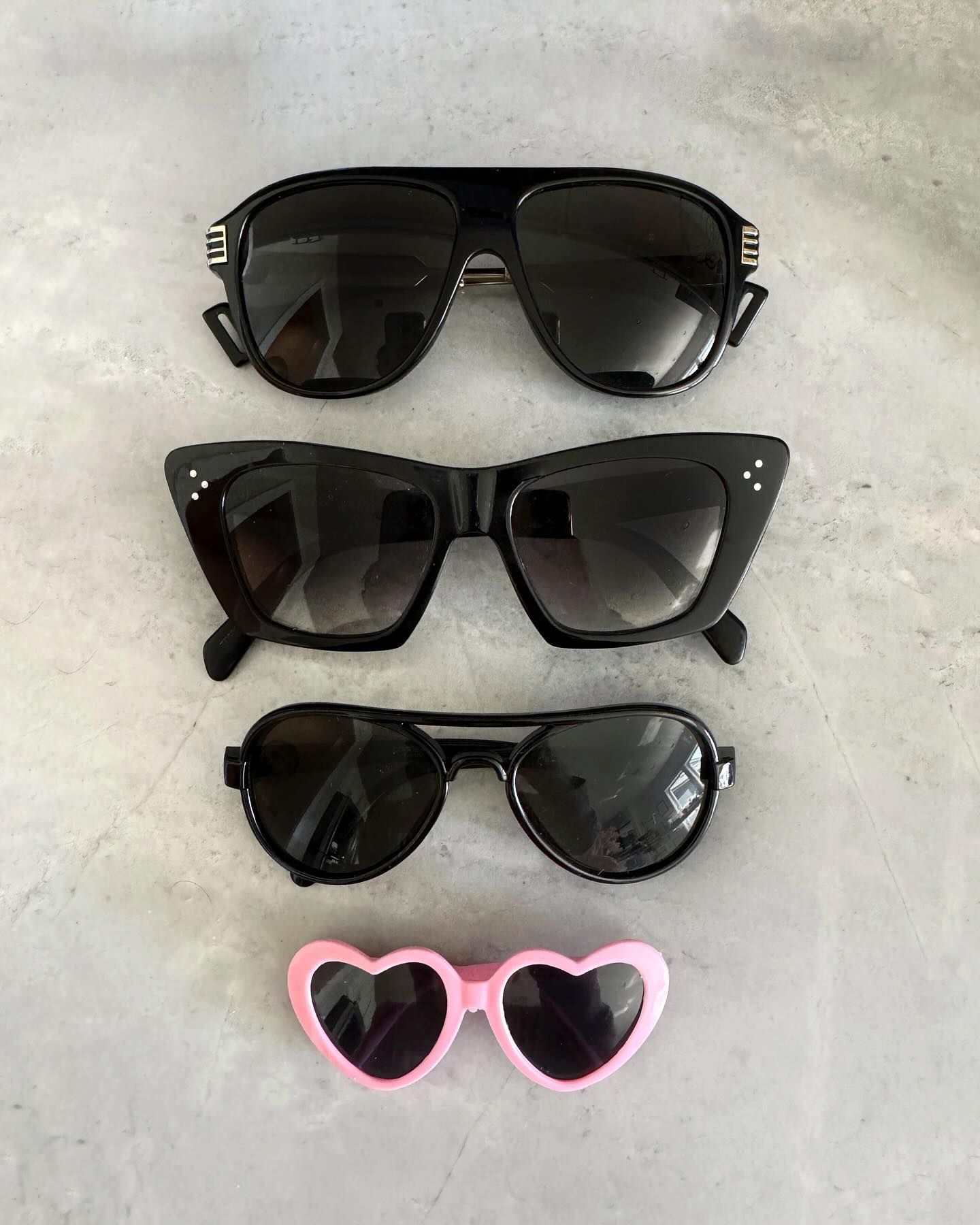 Three pairs of sunglasses are stacked on top of each other on a table.