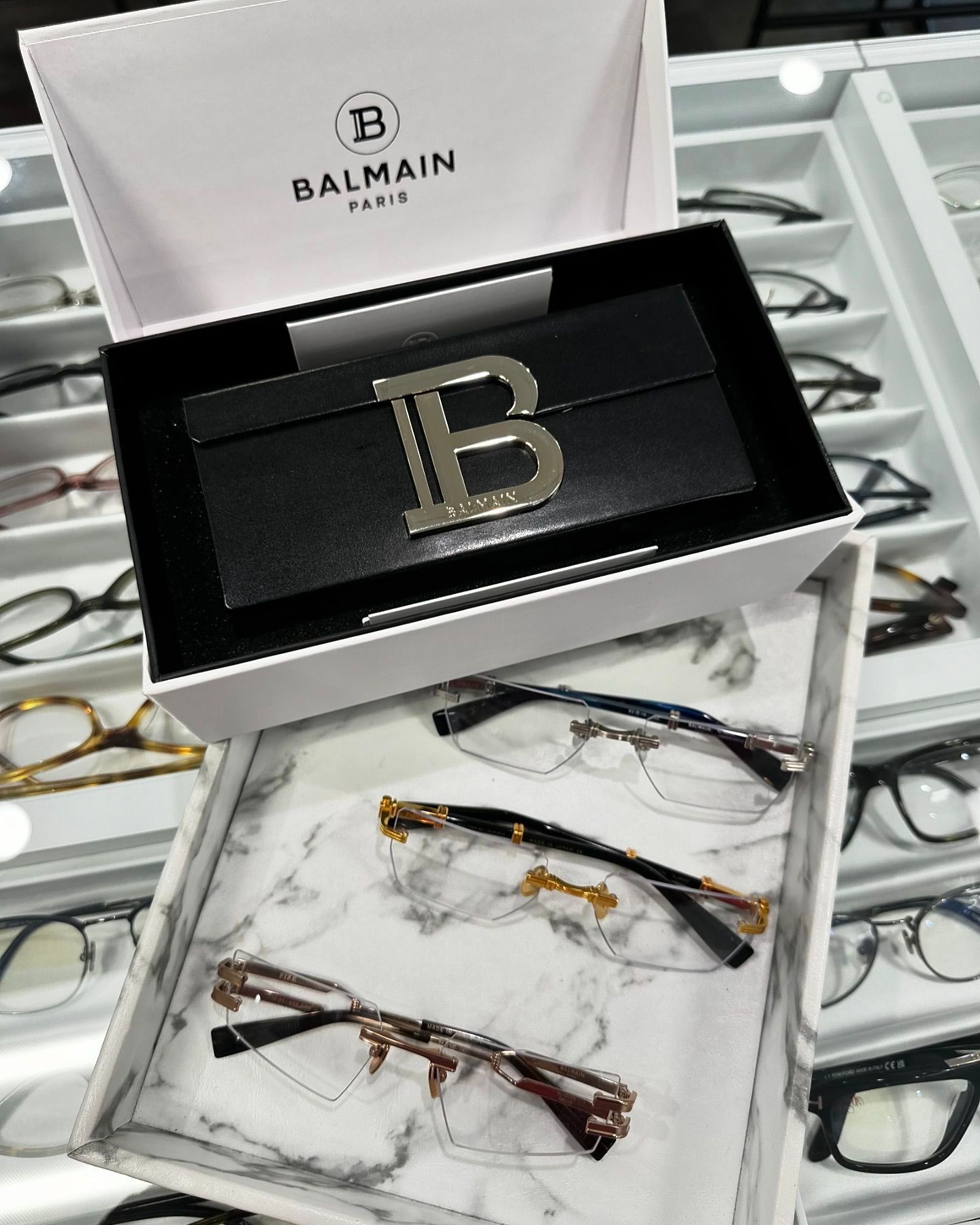 A box of balmain glasses is sitting on top of a tray of glasses.