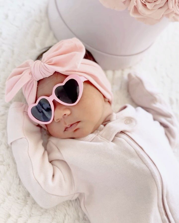 A baby wearing heart shaped sunglasses and a pink headband