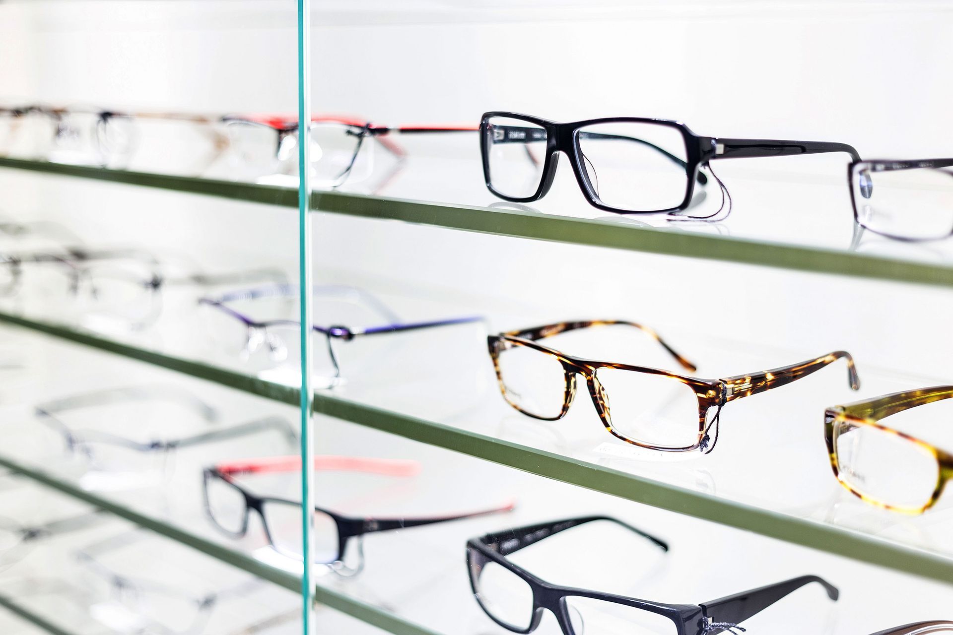 A row of glasses sitting on top of a glass shelf.