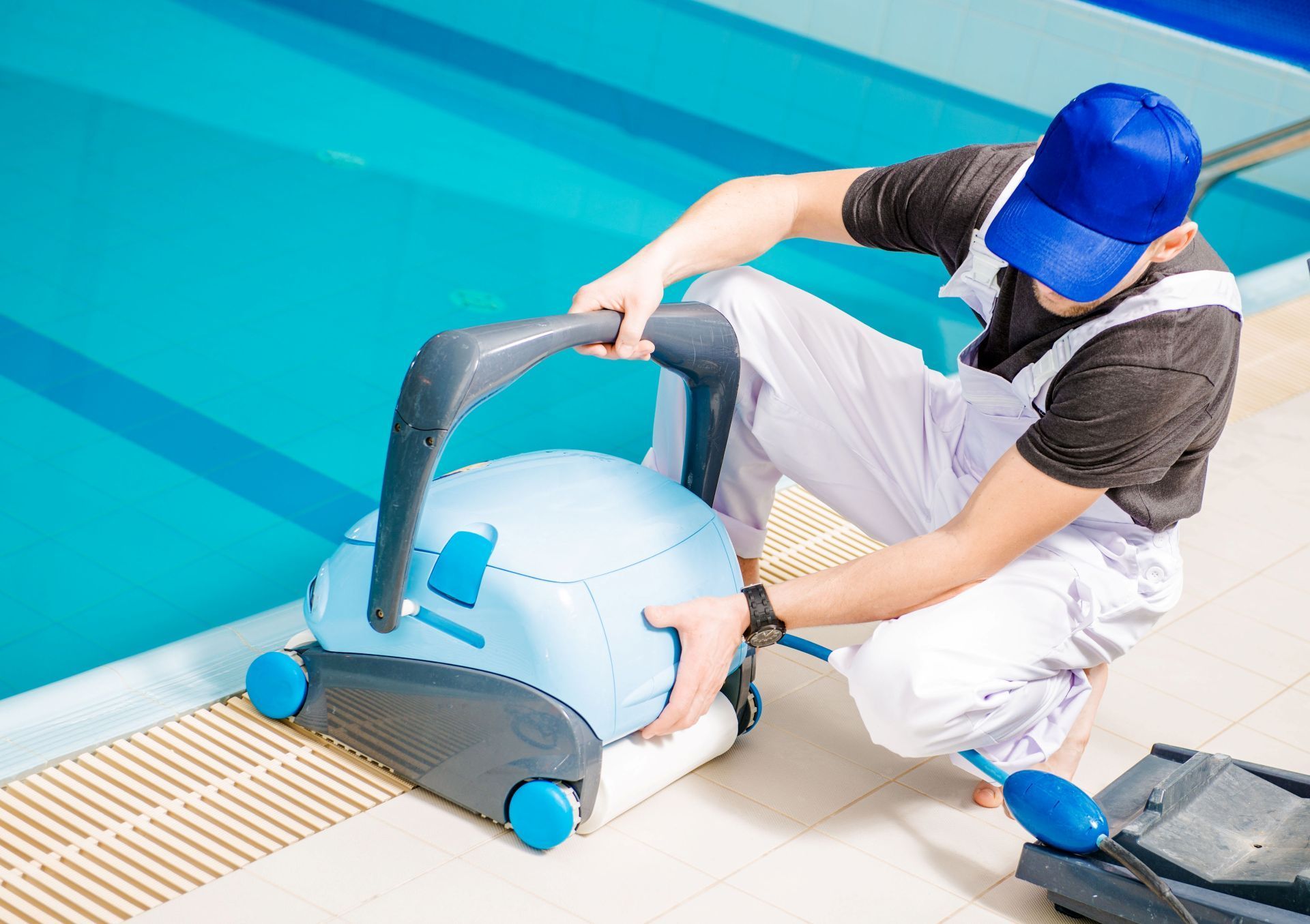 Pool cleaner placing a robotic pool cleaner in a blue swimming pool.