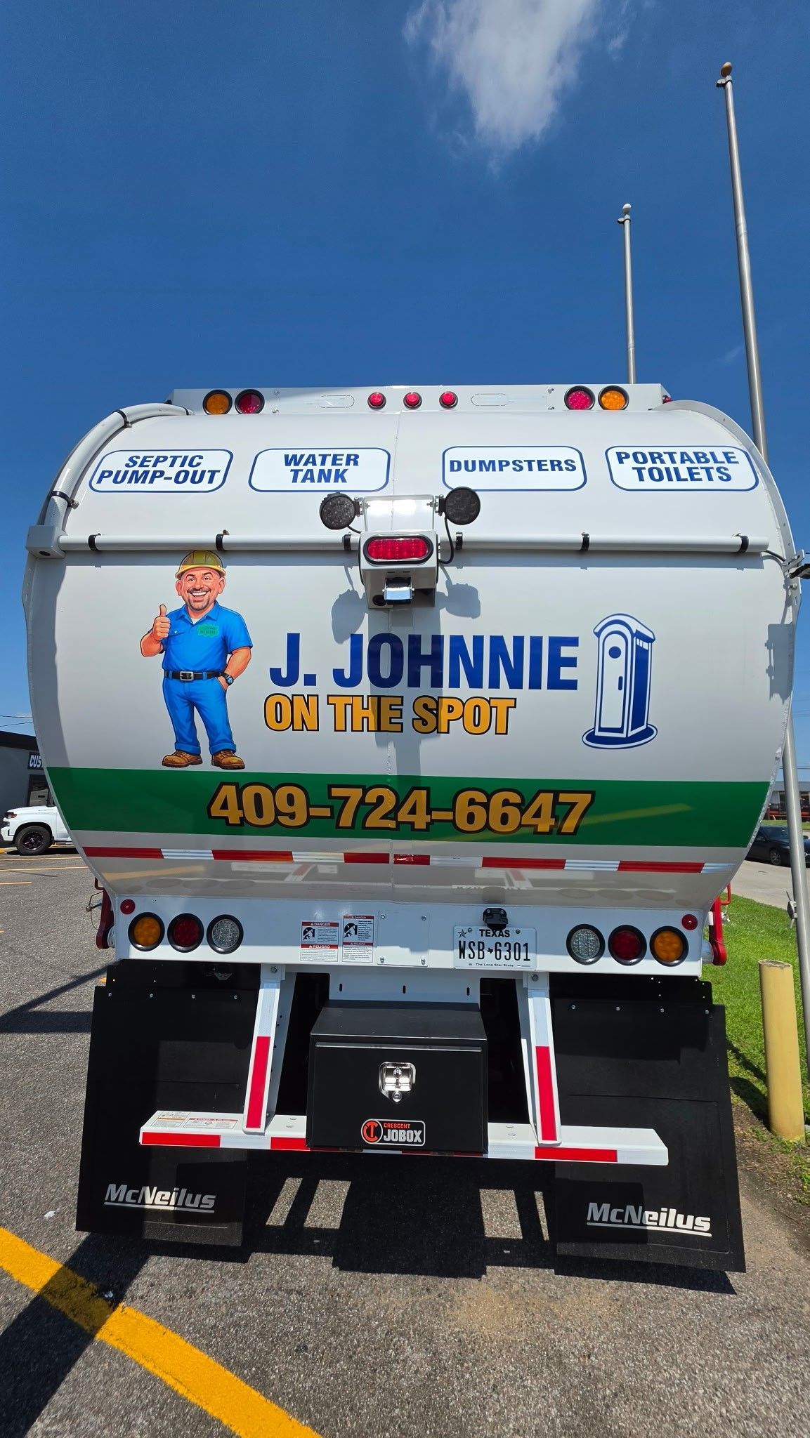 White septic truck with “J. JOHNNIE” branding, cartoon plumber, and phone number parked outdoors.
