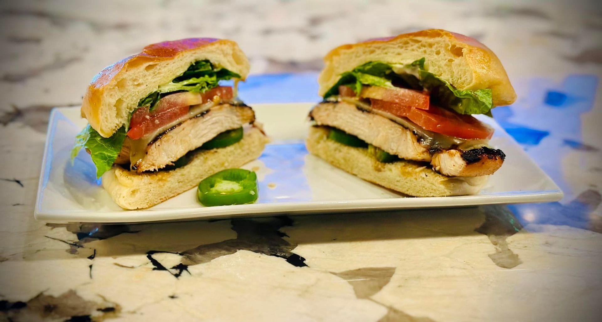 Two sandwiches are cut in half on a white plate.