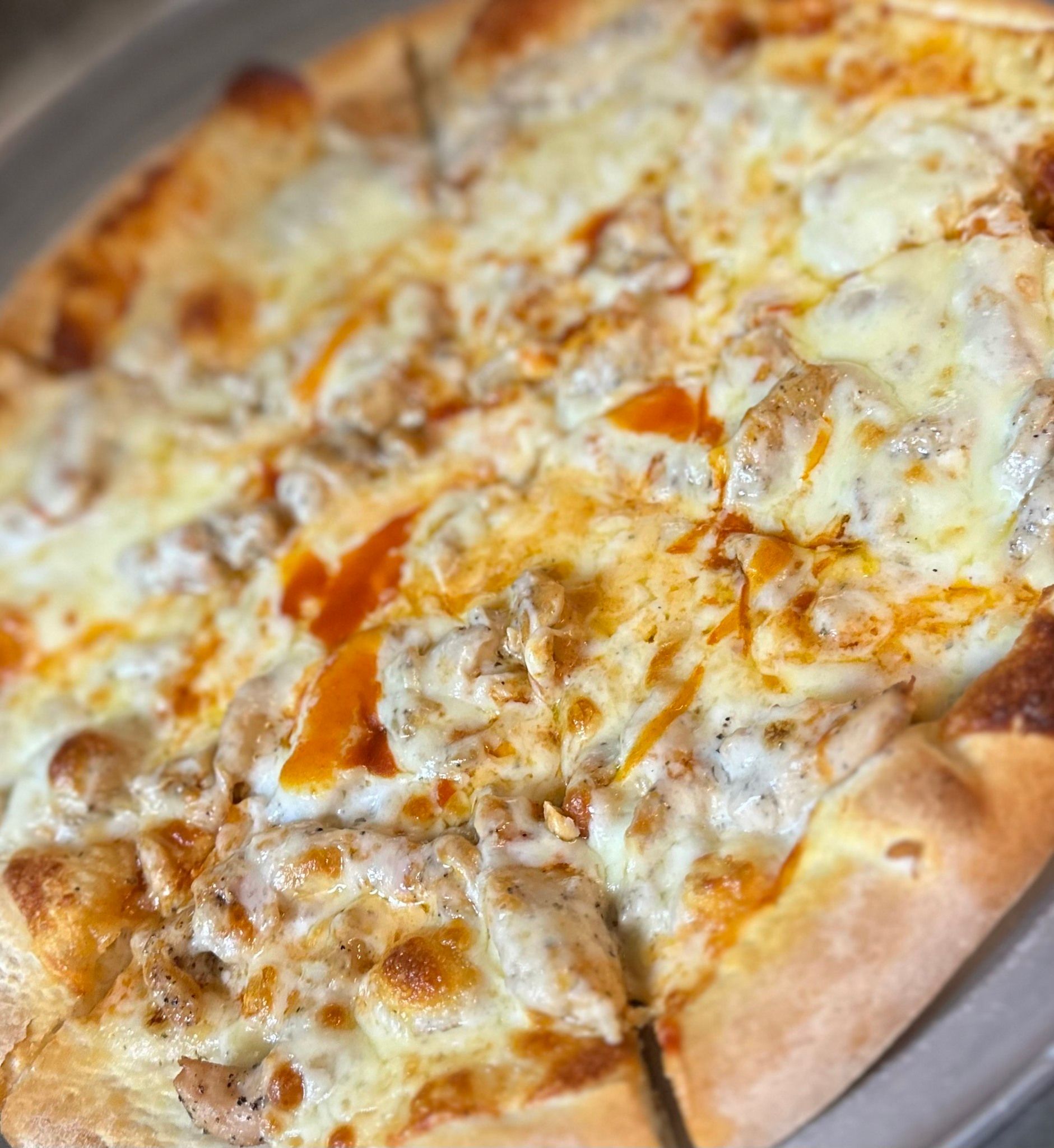 A close up of a pizza with chicken and cheese on a plate.