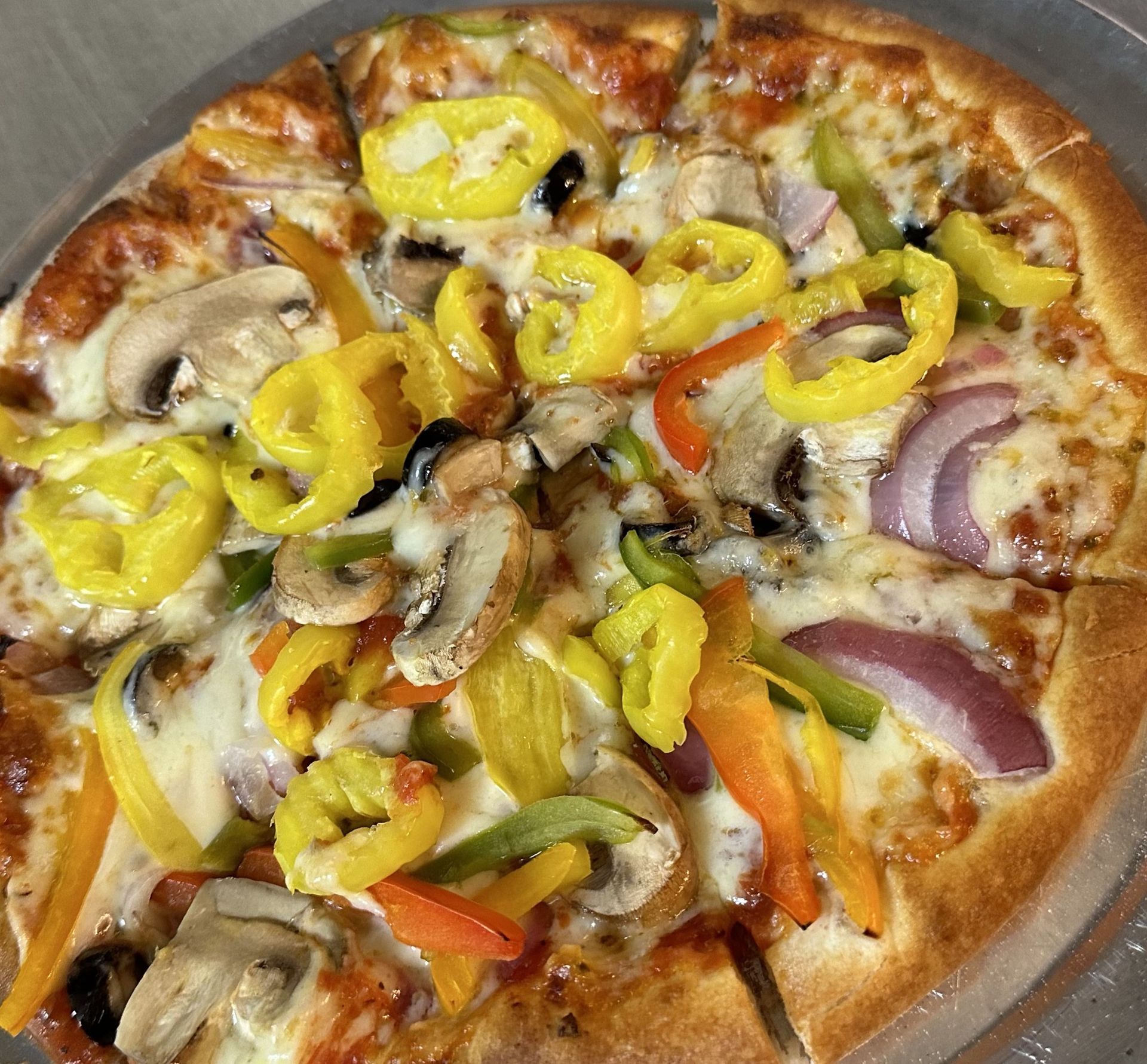 A pizza with mushrooms , peppers , onions and cheese on a plate.