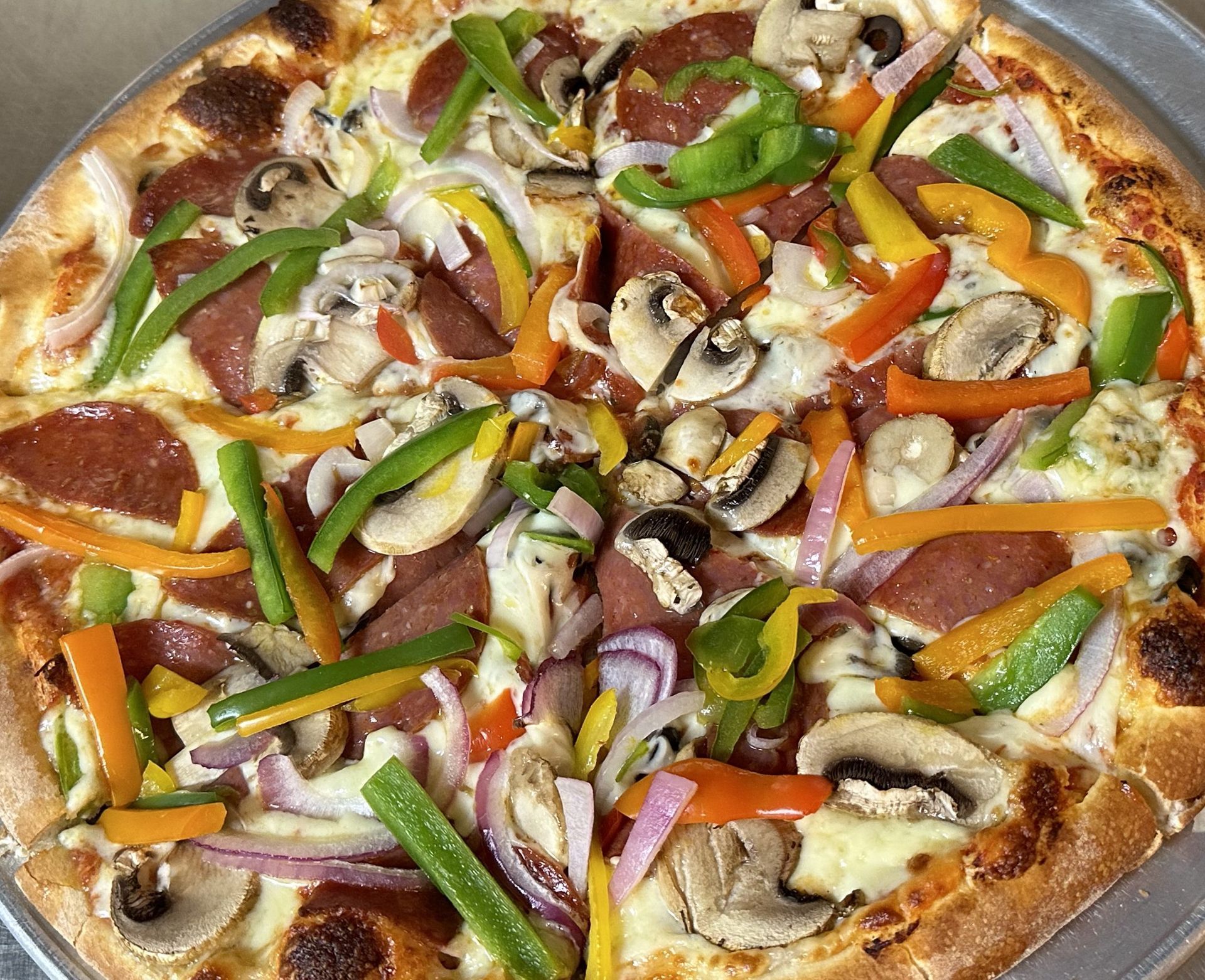 A pizza with pepperoni , mushrooms , onions and peppers on it