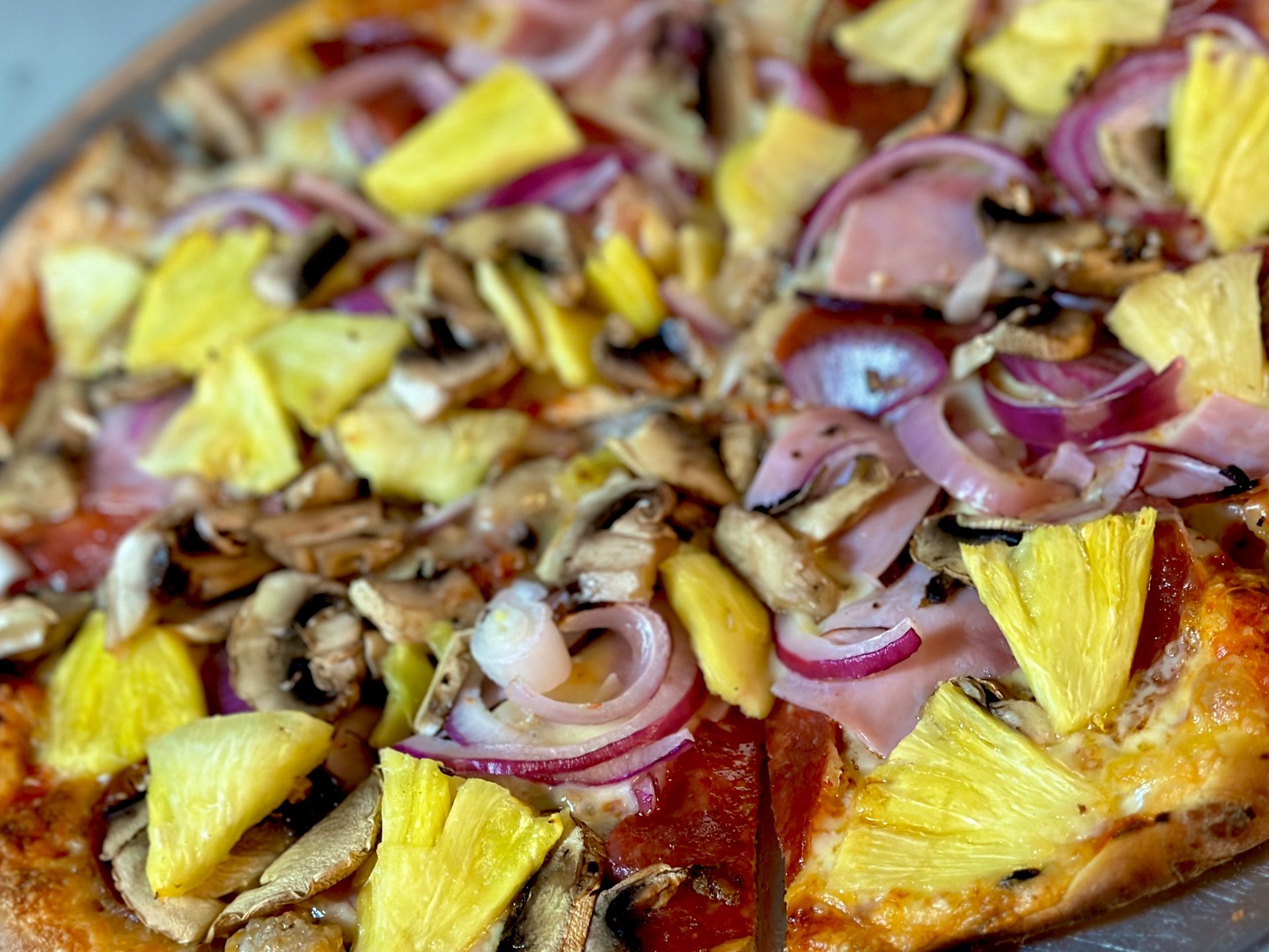 A pizza with pineapple , mushrooms , onions and pepperoni on it.