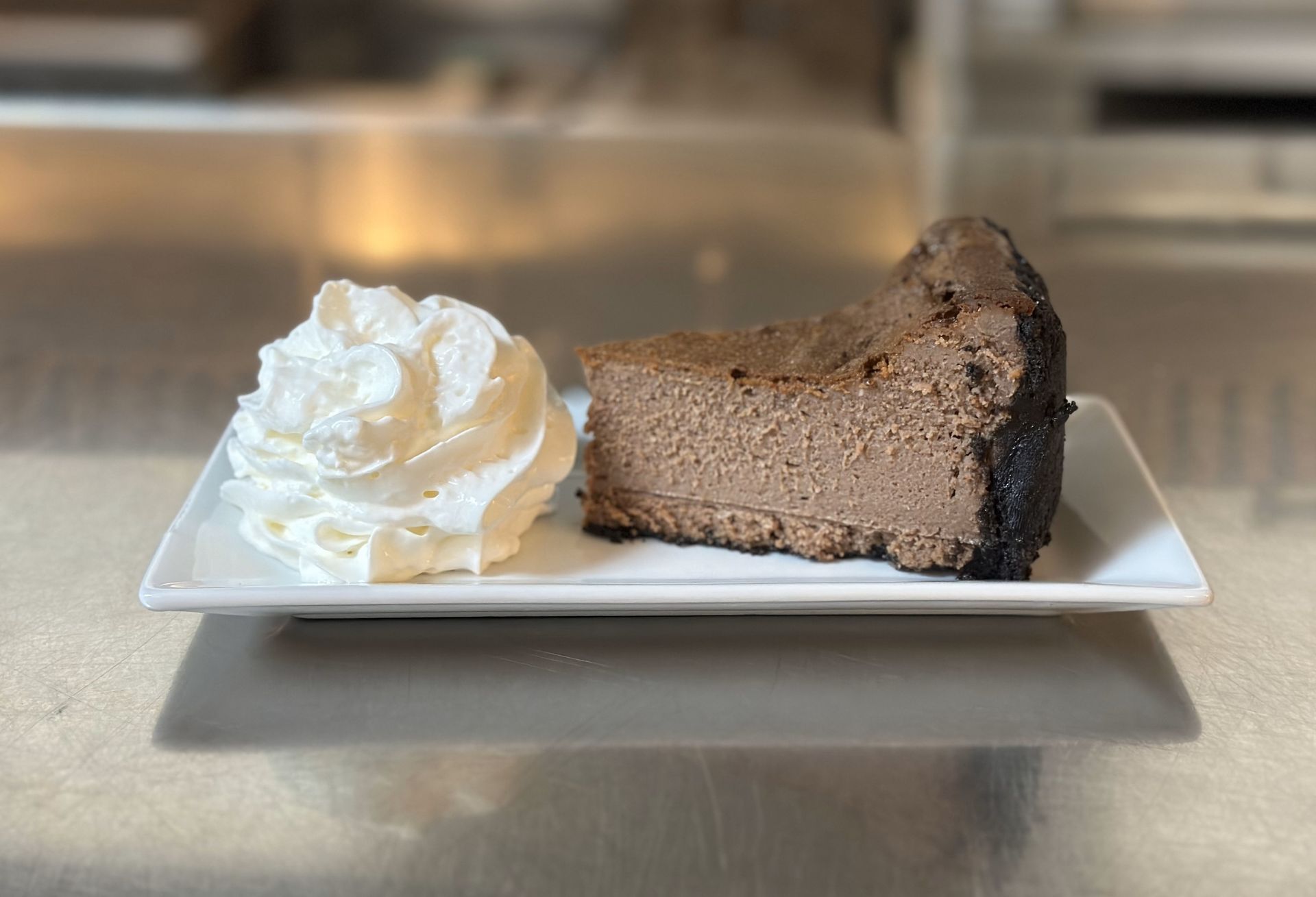 A slice of chocolate cheesecake with whipped cream on a white plate.