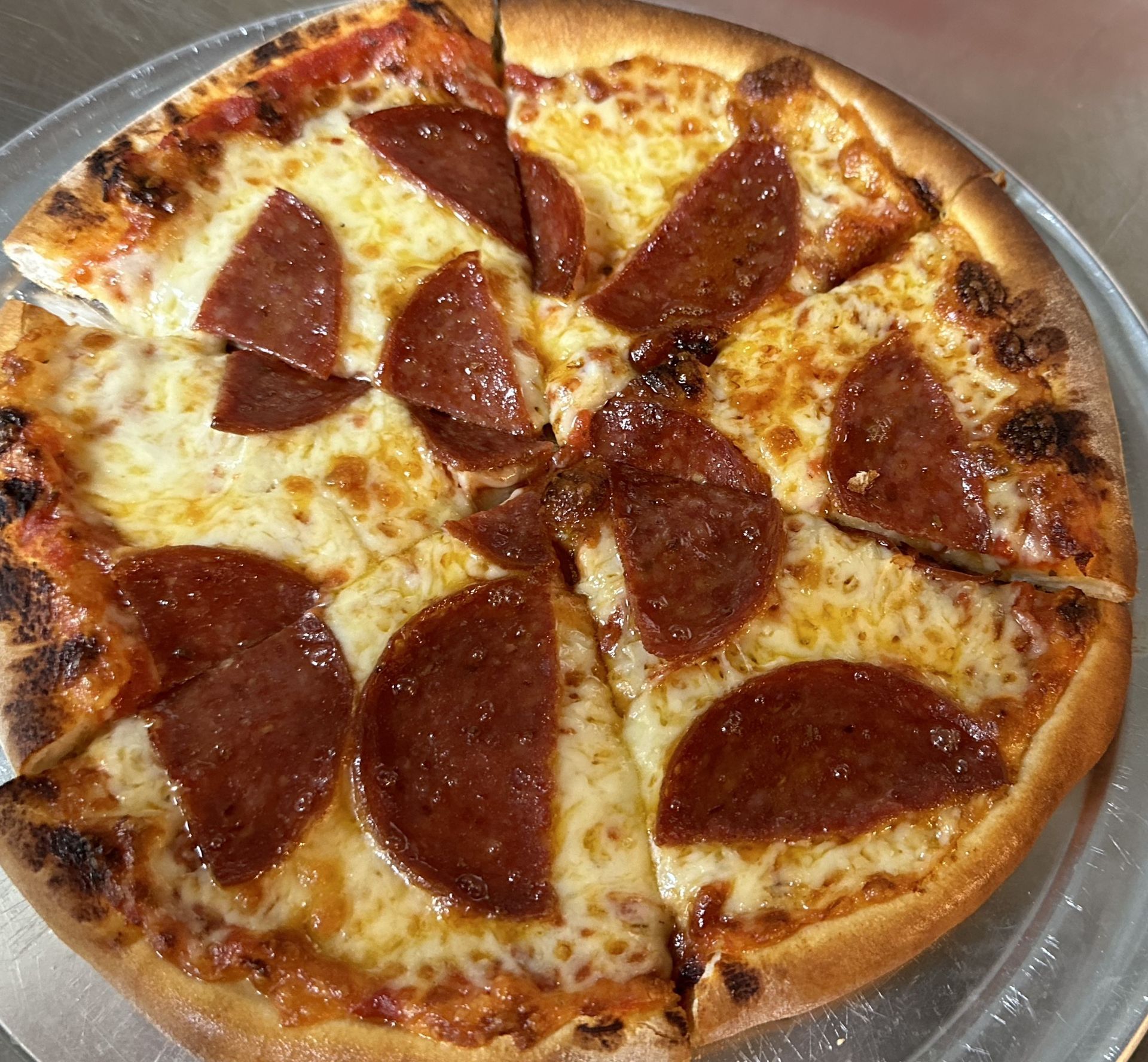 A pepperoni pizza with cheese and pepperoni slices on a pizza pan.