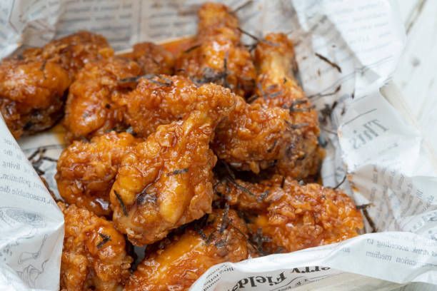 A close up of fried chicken wings on a piece of newspaper