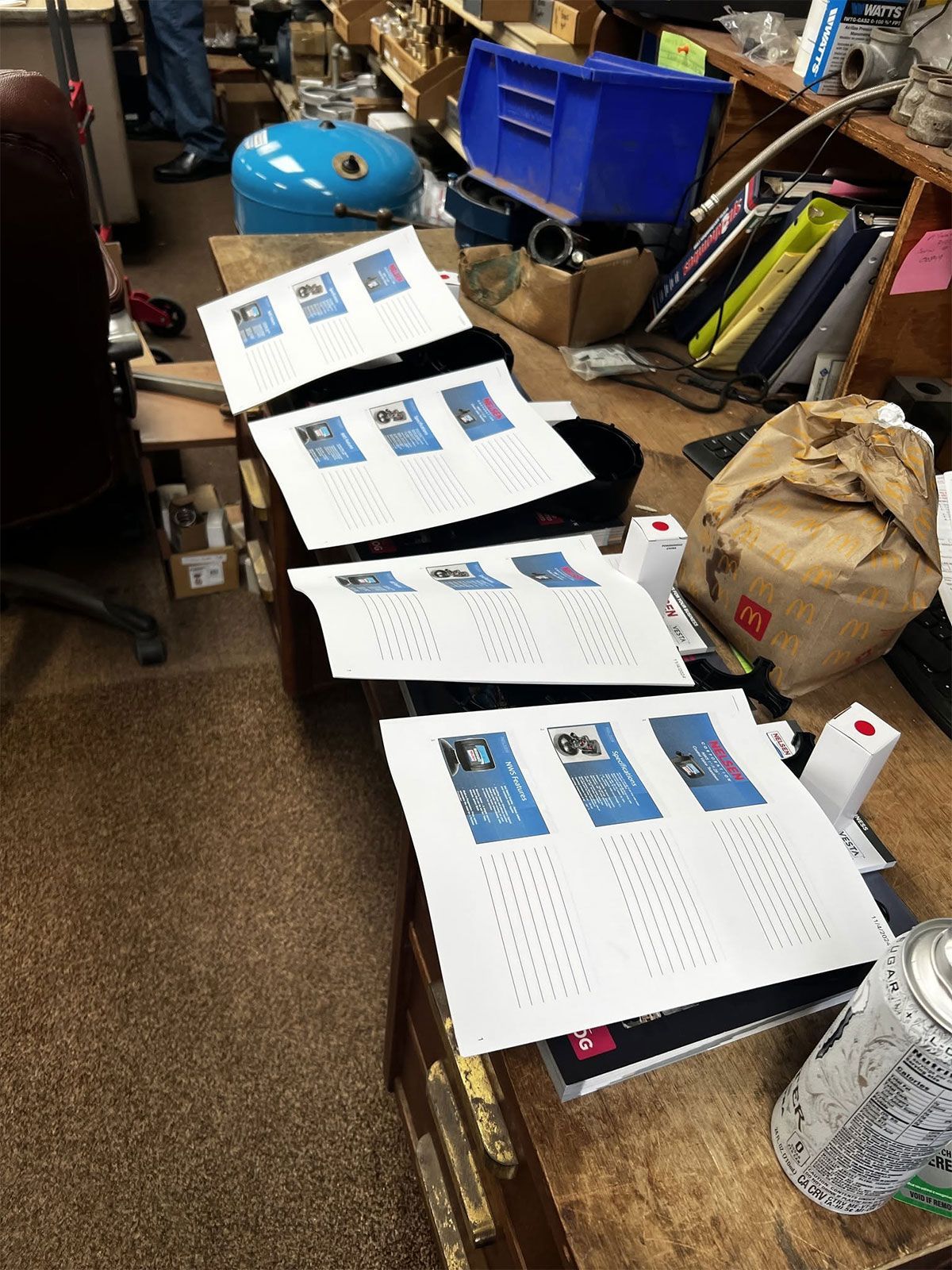 Floor with several printed pages laid out in a cluttered storage room.