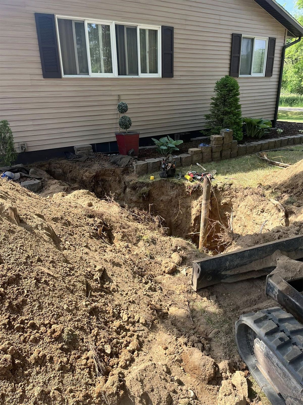 House exterior with a large dirt excavation and a construction machine in the foreground
