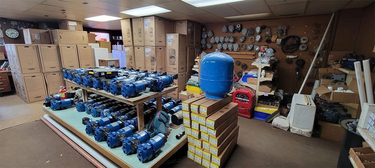 Indoor workshop with stacked blue equipment and boxes, plus tools and storage shelves along the back wall