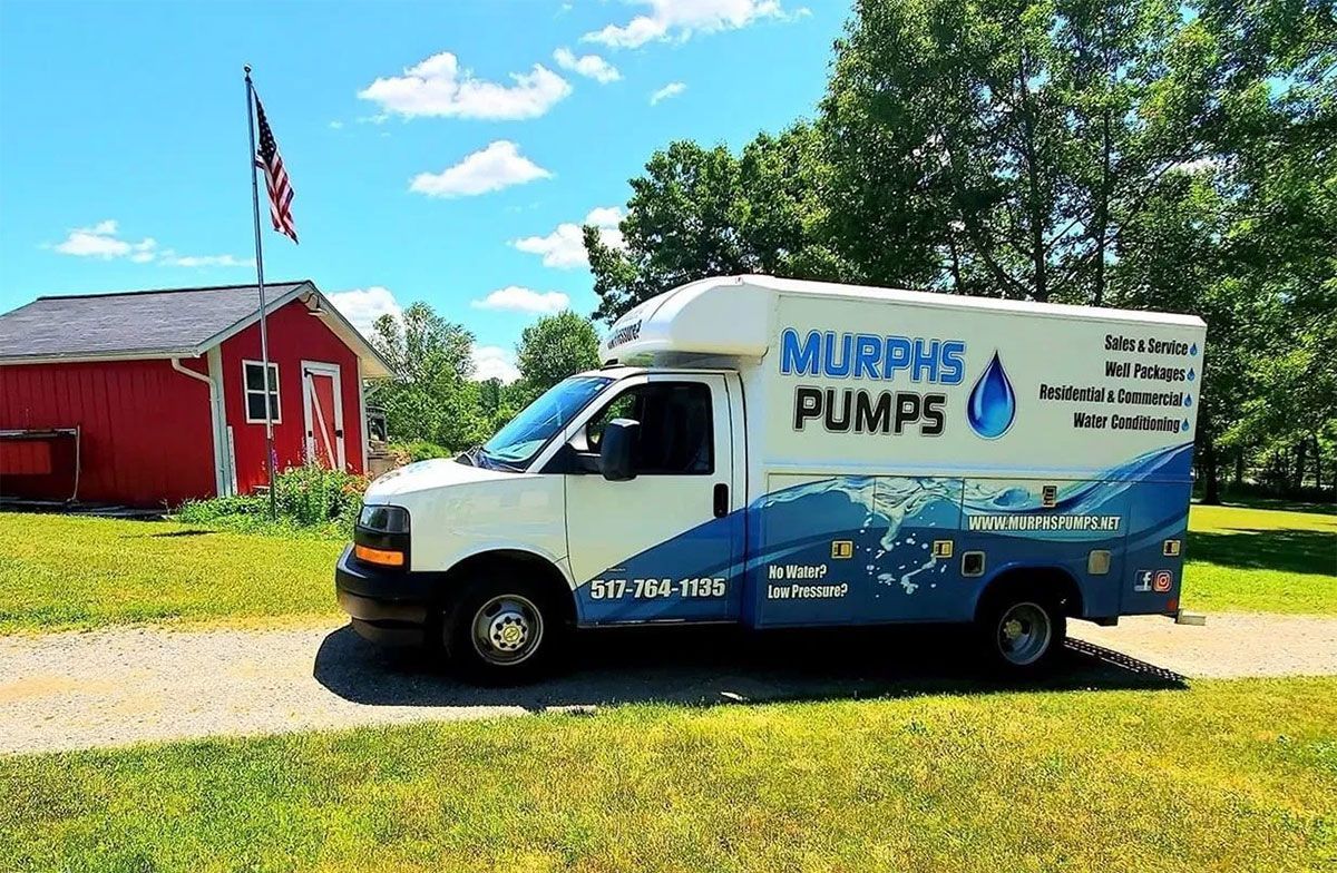 Murphy’s Pumps service van parked by a red barn on a sunny rural road