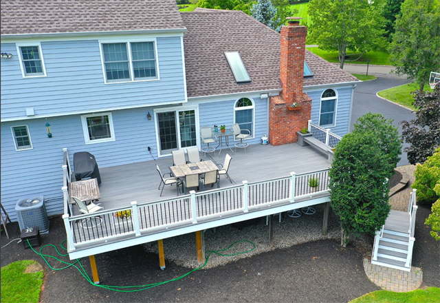 An aerial view of a blue house with a large deck.