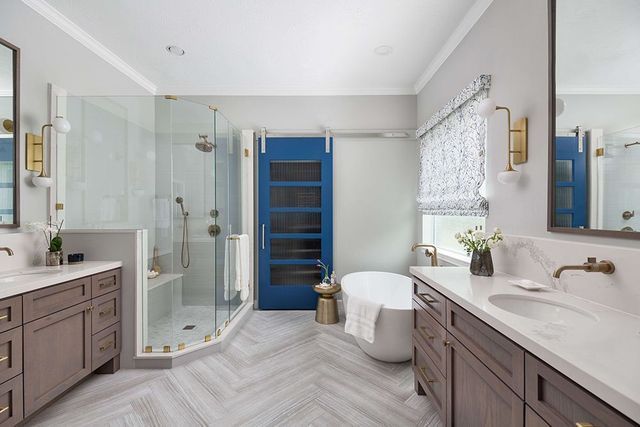 A bathroom with two sinks , a tub , a shower and a blue door.