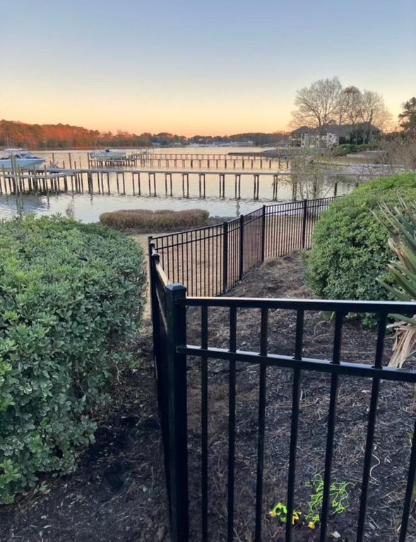 a black fence surrounds a body of water with a dock in the background