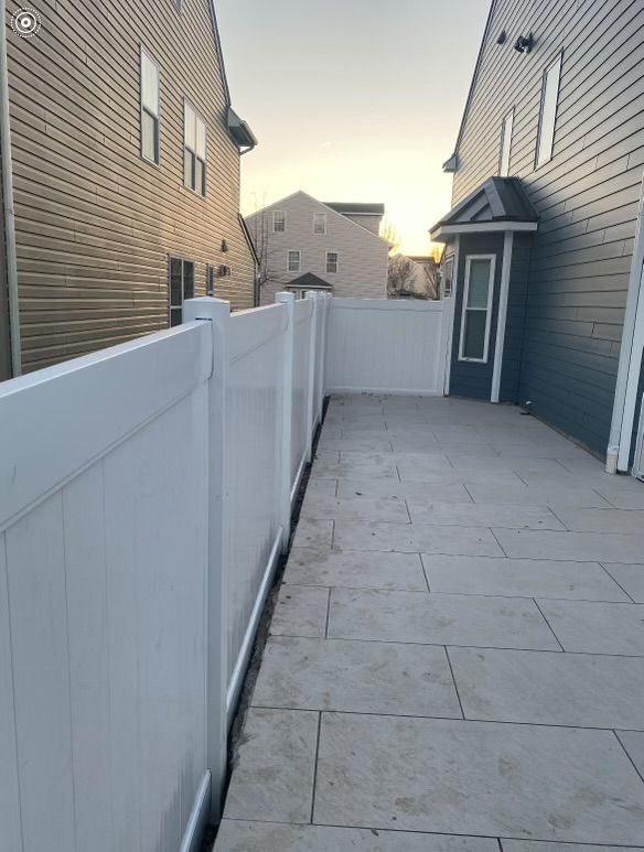 a white fence surrounds a patio between two houses