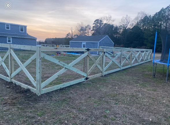 a wooden fence is sitting in the middle of a field in front of a house