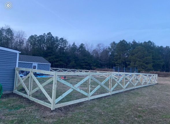 a long wooden fence is sitting in the middle of a grassy field