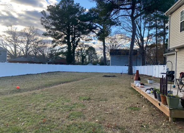 a backyard with a white fence and a wooden deck