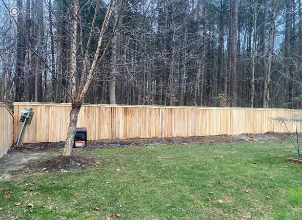 a wooden fence in a backyard with trees in the background