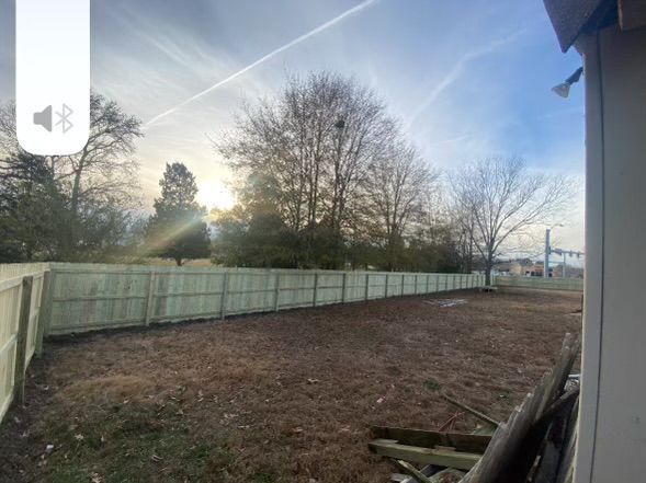 a view of a backyard with a white fence and trees