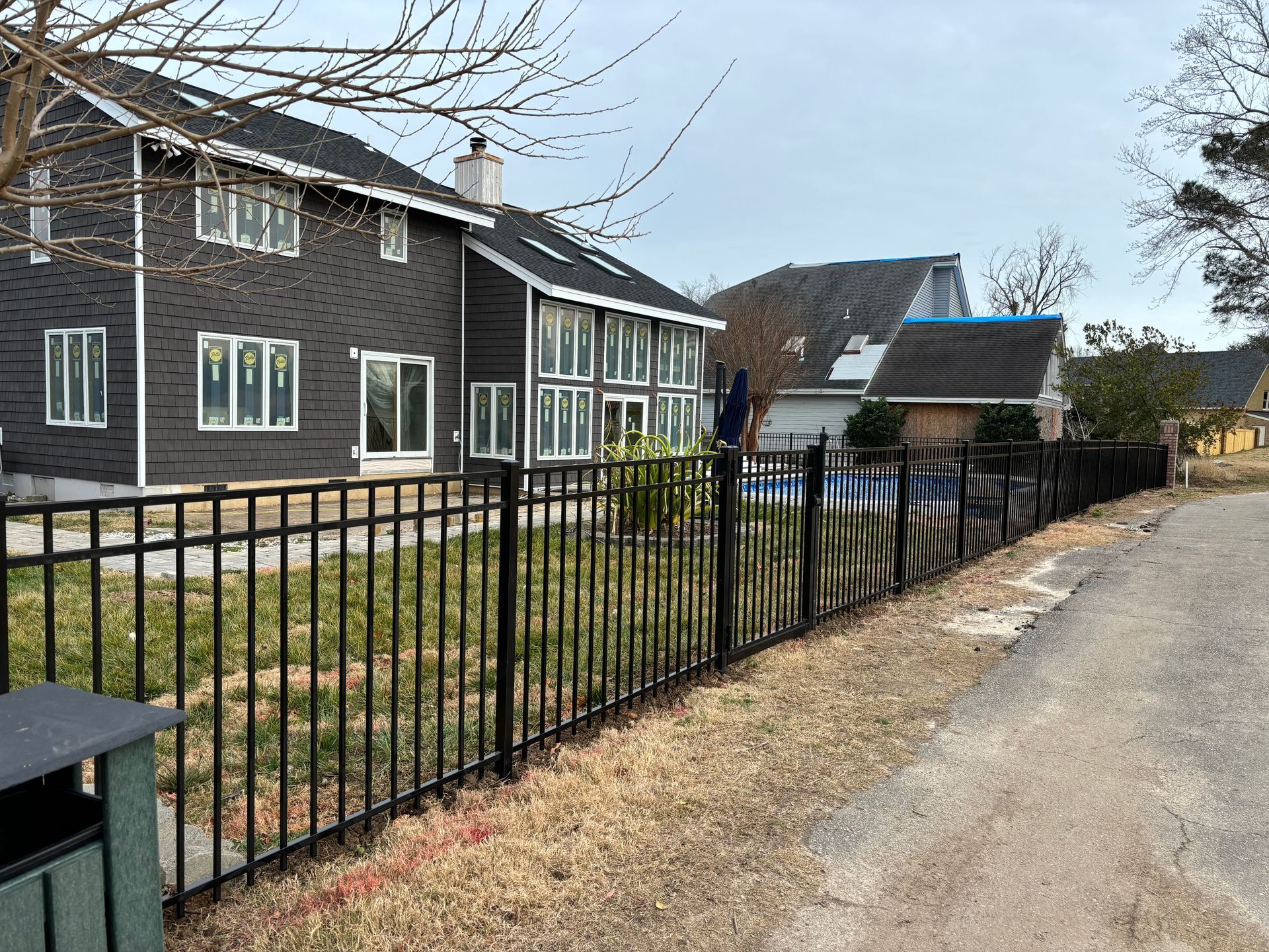 a black wrought iron fence surrounds a house in a residential area