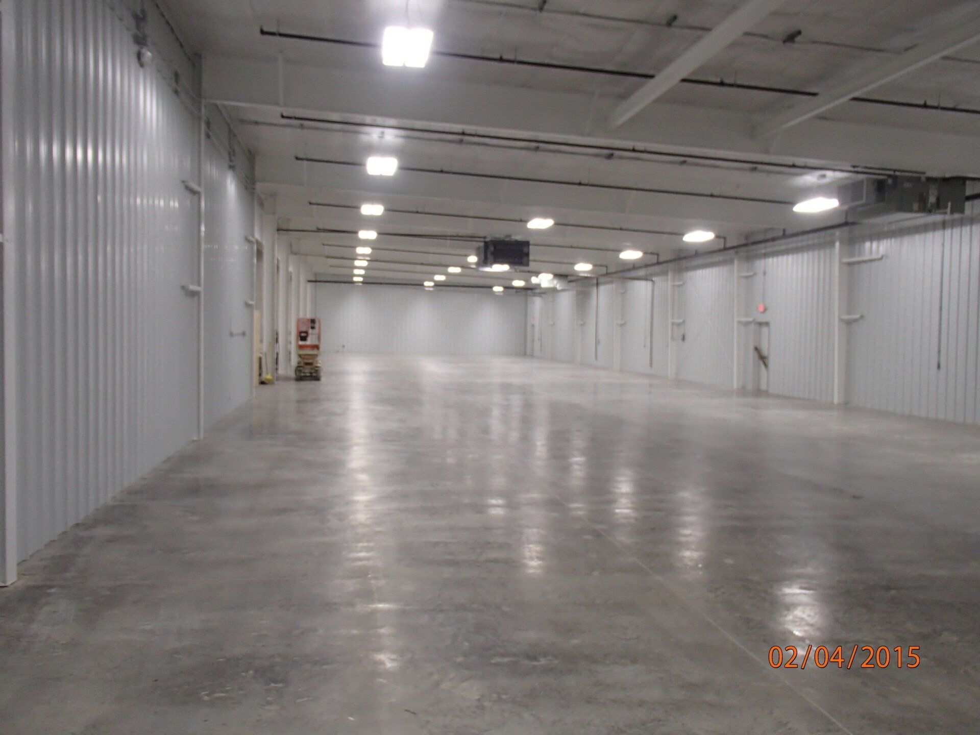 An empty warehouse with white walls and a concrete floor
