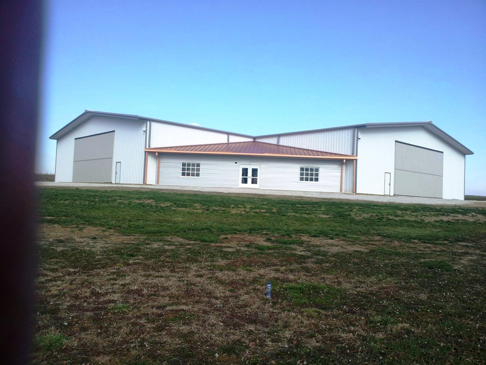 A large white building is sitting in the middle of a grassy field.