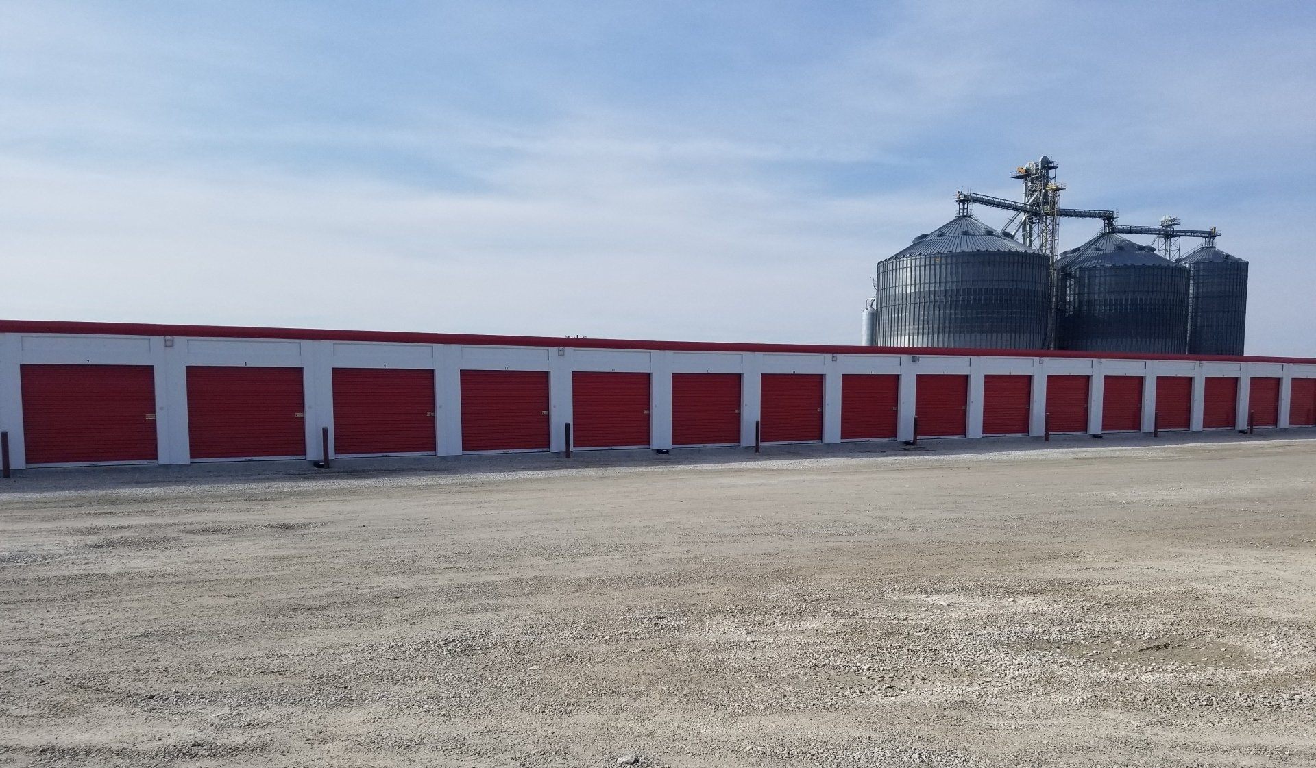 A row of red garage doors with a silo in the background