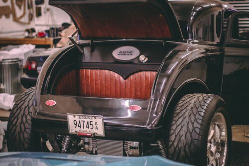 A black car with a license plate that says 94745 is parked in a garage.