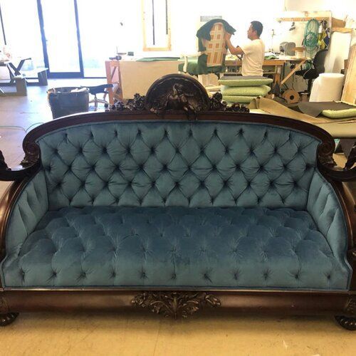 A man is working on a blue couch in a room.