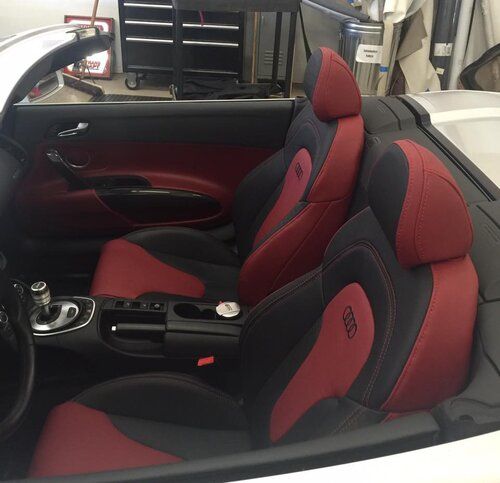 The inside of a convertible car with red and black seats