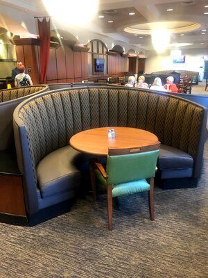 A restaurant with a round table and chairs in a booth.