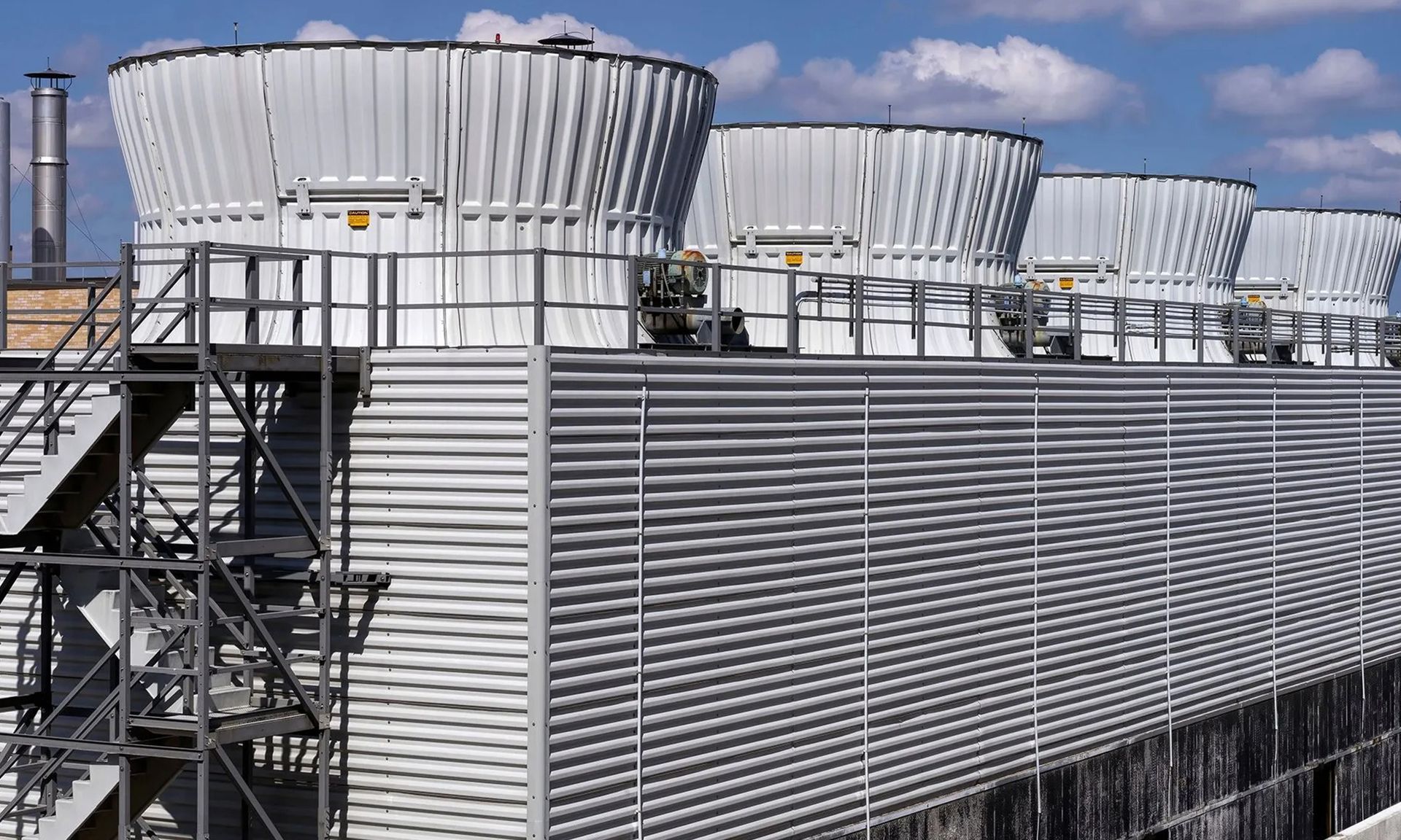 Industrial cooling towers on a rooftop against a blue sky