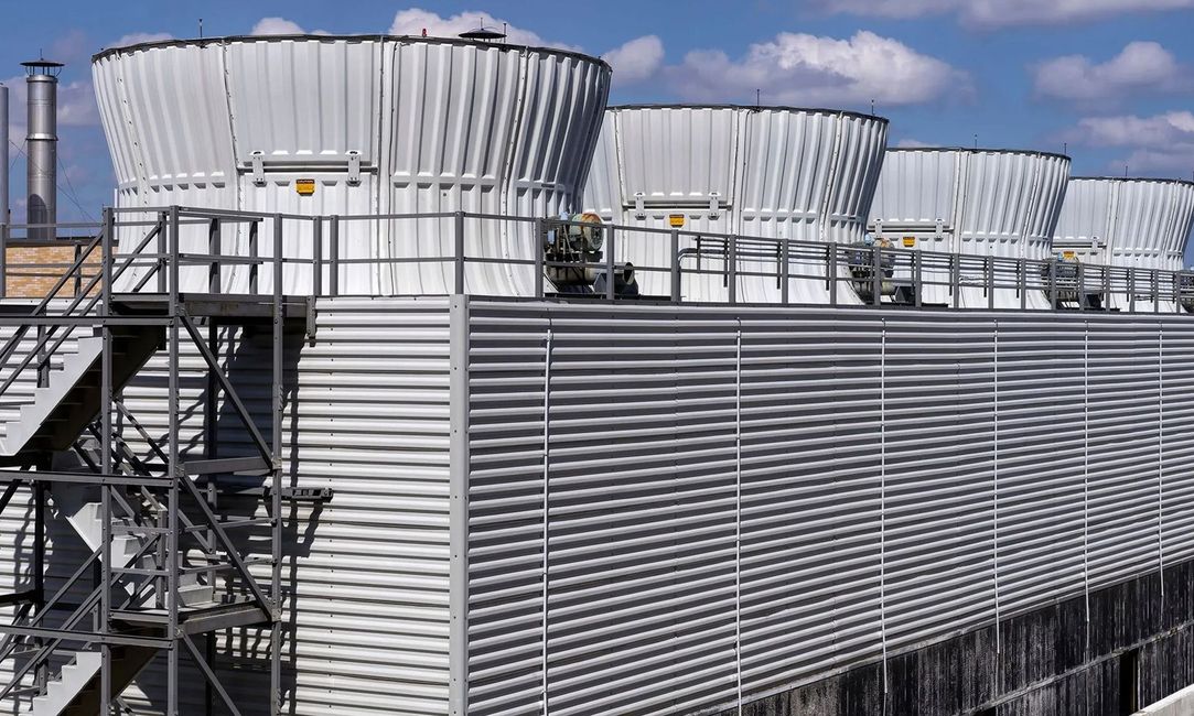 Industrial cooling towers on a rooftop against a blue sky