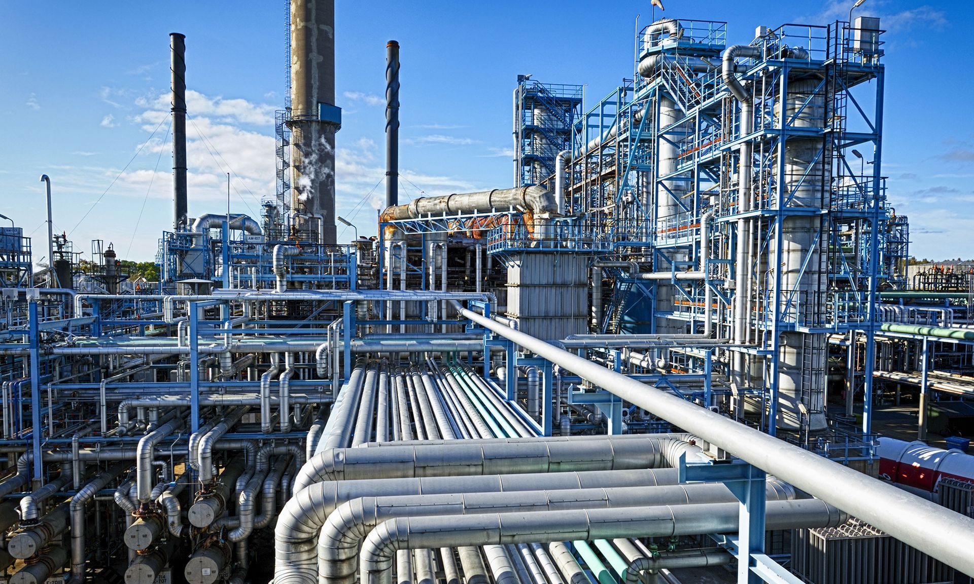 Industrial refinery with pipes, towers, and metal structures under a clear blue sky
