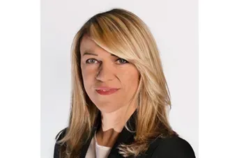 Headshot of a blonde woman in a black blazer against a white background