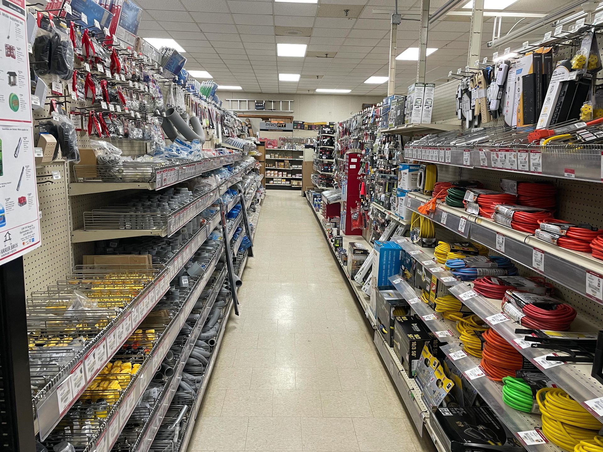 A long aisle of a hardware store filled with lots of shelves.