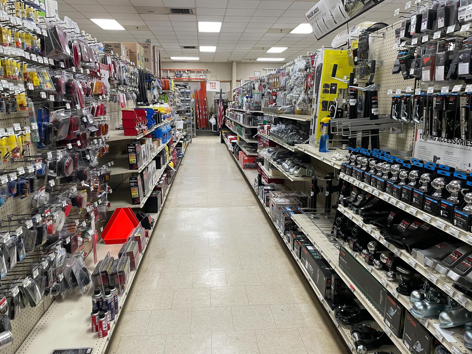 A long aisle of a hardware store filled with lots of products.